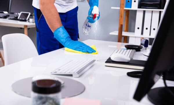Janitor cleaning white desk in office Janitor cleaning white desk in modern office