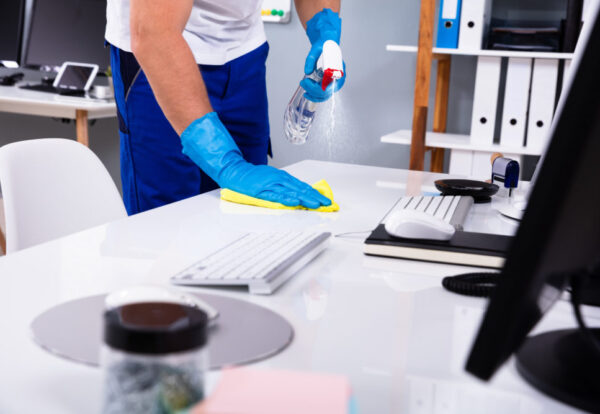 Janitor cleaning white desk in office Janitor cleaning white desk in modern office
